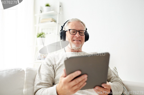 Image of senior man with tablet pc and headphones at home