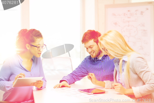 Image of smiling team with table pc and papers working