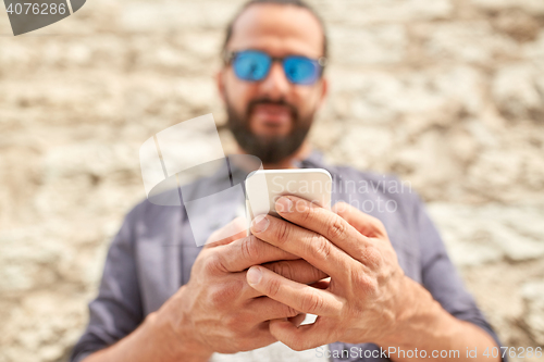 Image of close up of man with smartphone at stone wall