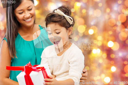 Image of happy mother and girl with gift box over lights