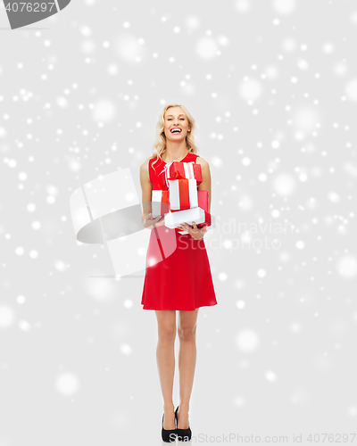 Image of happy woman in red dress holding christmas gifts