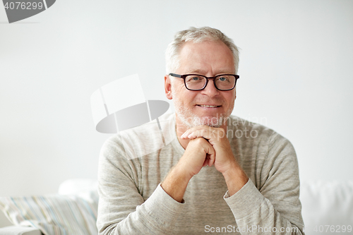 Image of smiling senior man in glasses sitting on sofa