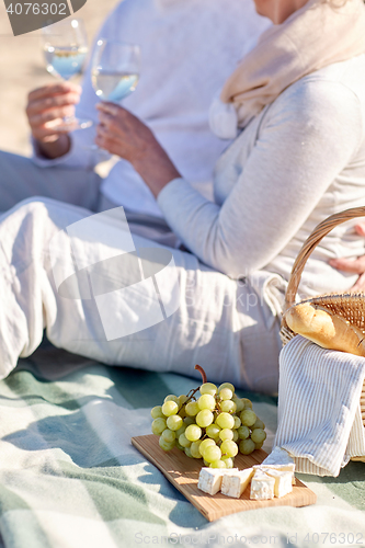 Image of happy senior couple having picnic on summer beach