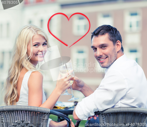 Image of smiling couple drinking wine in cafe