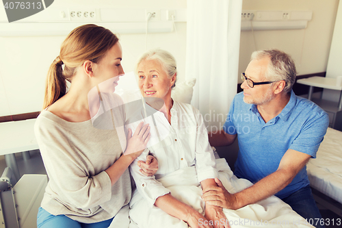 Image of happy family visiting senior woman at hospital