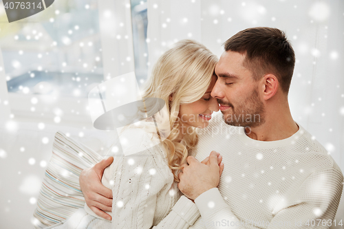 Image of happy couple covered with plaid on sofa at home