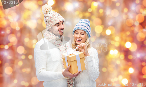 Image of smiling couple in winter clothes with gift box