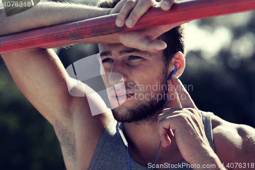 Image of young man with earphones and horizontal bar