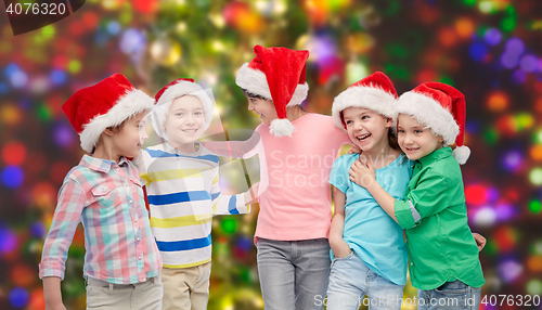 Image of happy little children in santa hats hugging