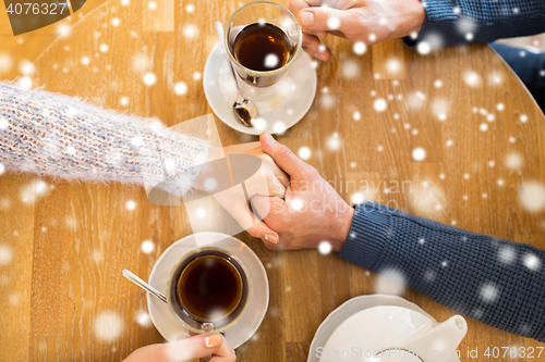 Image of close up of couple holding hands at restaurant