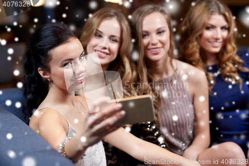 Image of women with smartphone taking selfie at night club