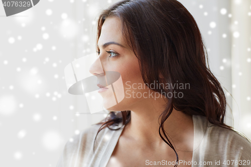 Image of close up of woman looking through window at home