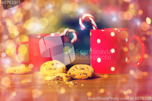 Image of christmas candy canes and cups on wooden table