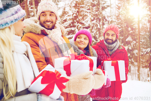 Image of happy friends with gift boxes in winter forest