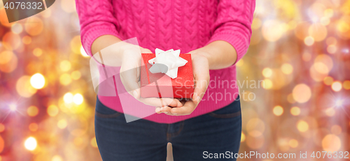 Image of close up of woman in pink sweater holding gift box