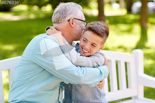 Image of grandfather and grandson hugging at summer park