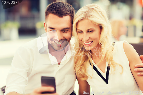 Image of happy couple with smatphone at city street cafe