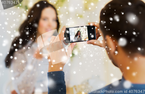 Image of man taking picture of woman by smartphone at cafe