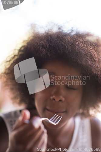 Image of a young African American woman eating pasta