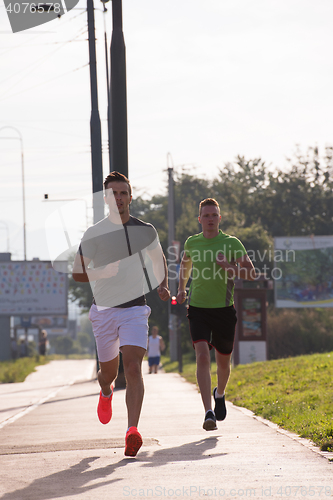 Image of Two young men jogging through the city