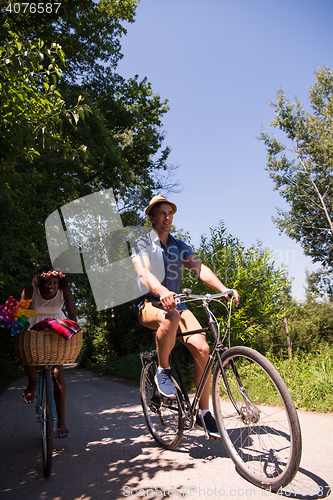 Image of Young multiethnic couple having a bike ride in nature