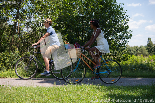 Image of Young multiethnic couple having a bike ride in nature