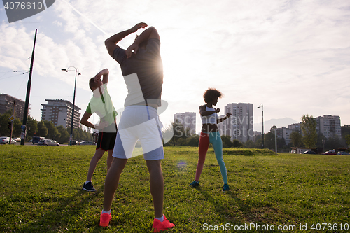 Image of multiethnic group of people stretching in city park