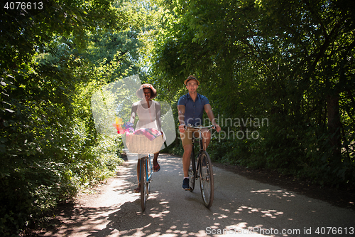 Image of Young multiethnic couple having a bike ride in nature