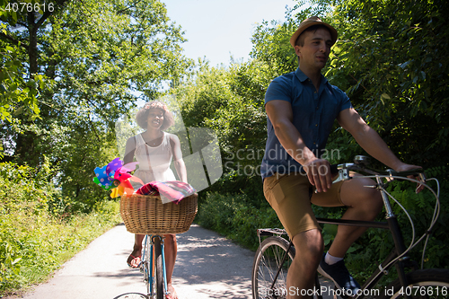 Image of Young multiethnic couple having a bike ride in nature