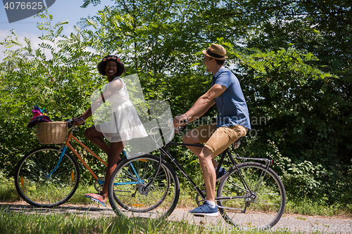 Image of Young multiethnic couple having a bike ride in nature