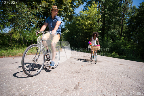 Image of Young multiethnic couple having a bike ride in nature