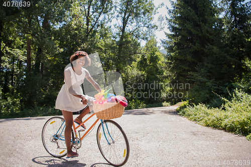 Image of pretty young african american woman riding a bike in forest
