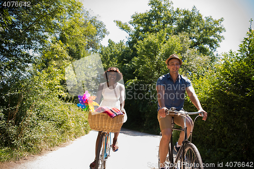 Image of Young multiethnic couple having a bike ride in nature