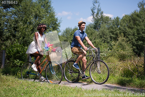 Image of Young multiethnic couple having a bike ride in nature
