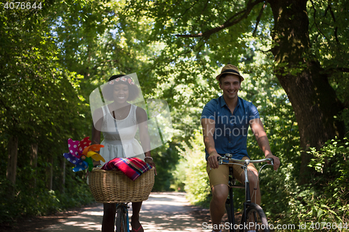 Image of Young multiethnic couple having a bike ride in nature