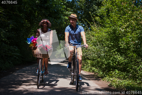 Image of Young multiethnic couple having a bike ride in nature