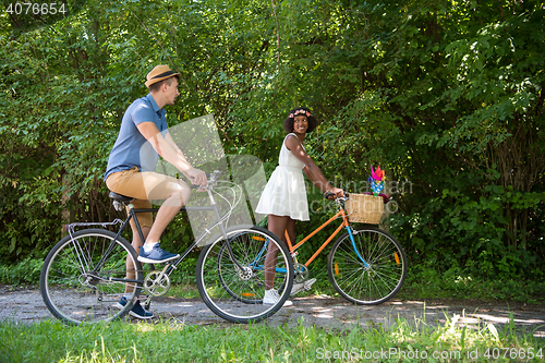 Image of Young multiethnic couple having a bike ride in nature