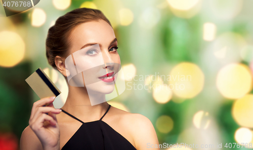 Image of beautiful woman with credit card over black