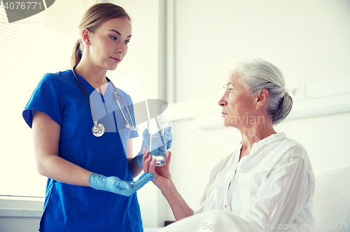 Image of nurse giving medicine to senior woman at hospital