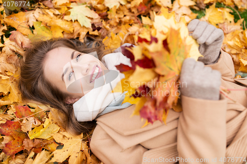 Image of beautiful happy woman lying on autumn leaves