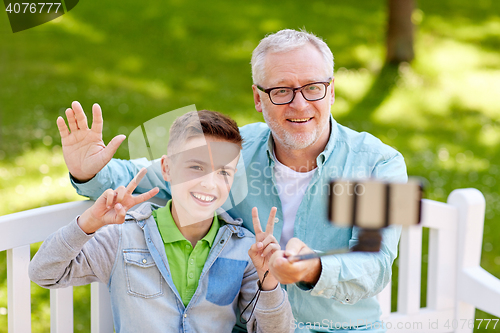 Image of old man and boy taking selfie by smartphone