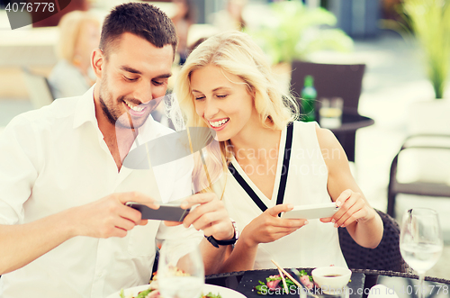 Image of happy couple with smatphone photographing food