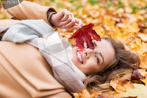 Image of beautiful happy woman lying on autumn leaves