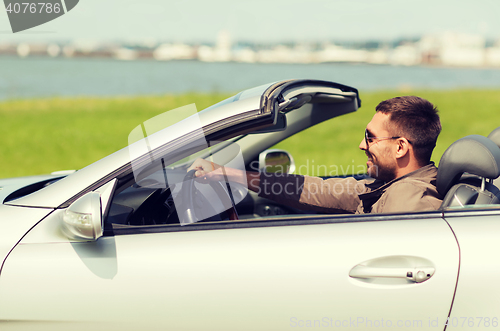 Image of happy man driving cabriolet car outdoors