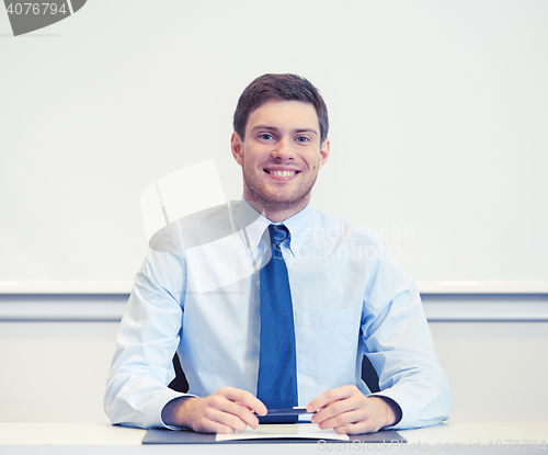 Image of smiling businessman sitting in office