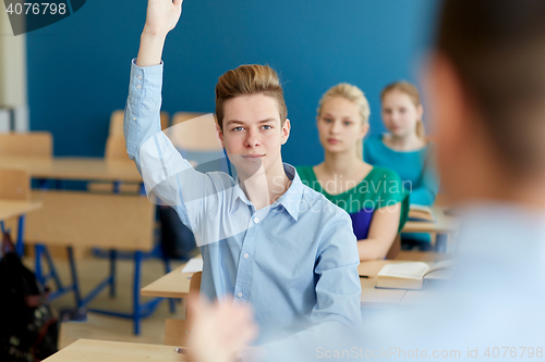 Image of happy student boy raising hand at school lesson