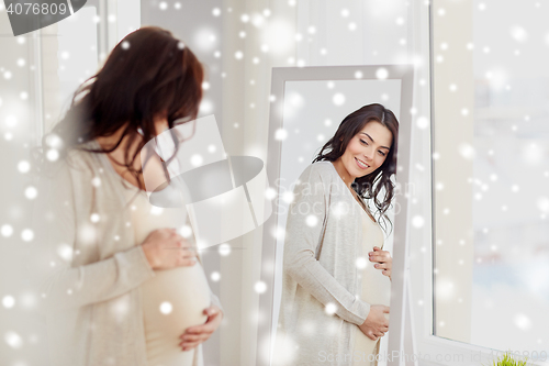 Image of happy pregnant woman looking to mirror at home