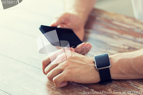 Image of close up of hands with smart phone and watch