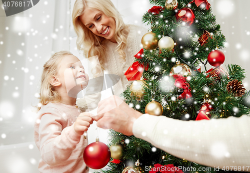 Image of happy family decorating christmas tree at home