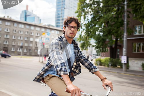 Image of young hipster man with bag riding fixed gear bike